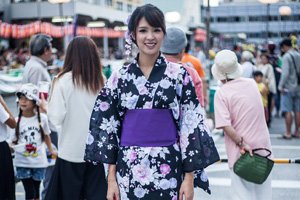 Frau im Schwarz-Weißem Yukata mit Blumenmuster und Lilanem Obi.